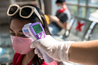 Cropped hand checking temperature of woman at airport