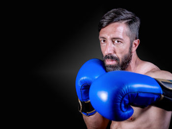 Close-up of shirtless man against black background