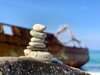 Stack of stones in sea against clear sky