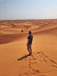 Full length rear view of man standing on desert