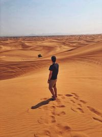 Full length rear view of man standing on desert