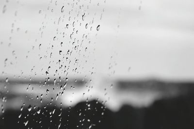 Close-up of wet window against sky