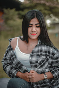 Portrait of a sitting indonesian woman wearing a plaid shirt