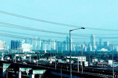 Electricity pylon and buildings in city against sky