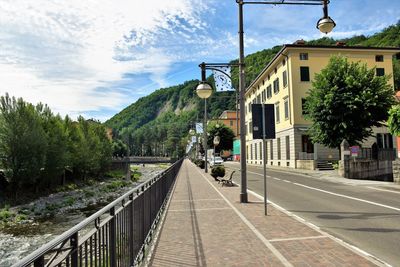 Street amidst trees and buildings against sky