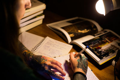 High angle view of woman writing book on table