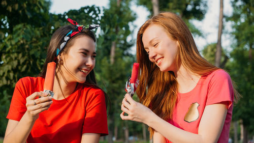 Outdoor portrait of happy three young woman holding an ice cream in summer park background. 