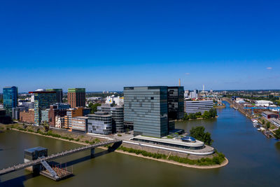 High angle view of river and buildings against clear blue sky