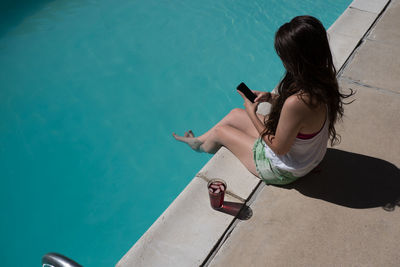 Rear view of woman sitting in swimming pool