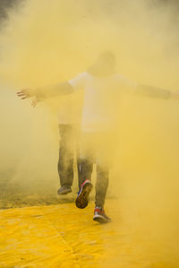 People walking amidst yellow powder paint during holi
