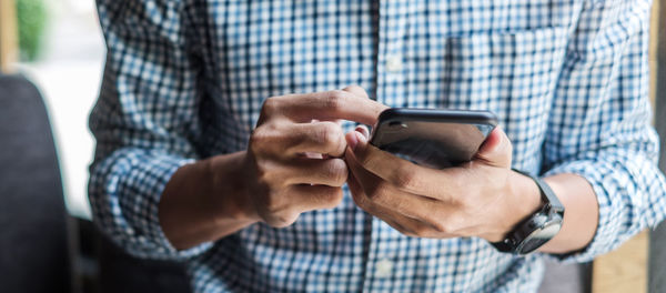 Midsection of man using mobile phone