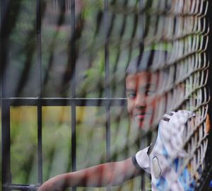 Portrait of boy looking through fence