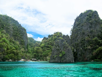 Scenic view of sea by mountain against sky