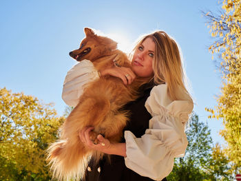 Portrait of woman with dog against sky