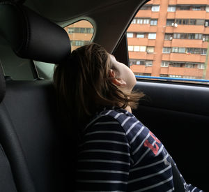 Girl looking through window while sitting in car