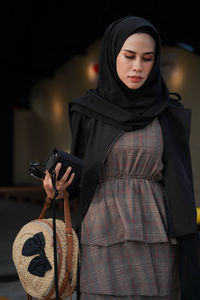 Beautiful woman with purse standing in room