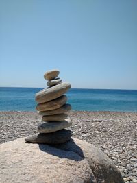 Stacked pebbles on shore against clear sky