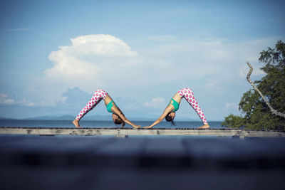 Side view of females exercising on pier