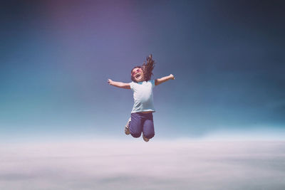 Young woman jumping against clear sky