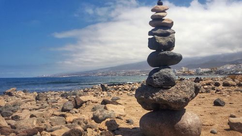 Stack of stones on beach against sky