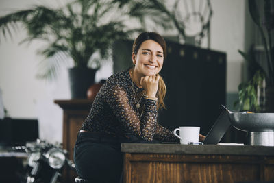 Portrait of a smiling woman sitting on table