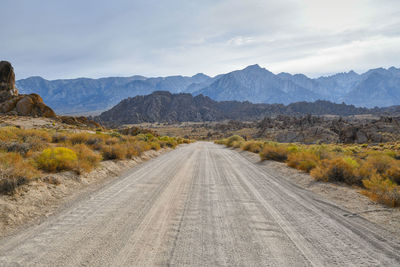 Road leading towards mountains against sky