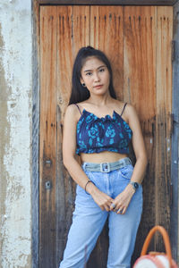 Portrait of beautiful woman standing against wooden wall