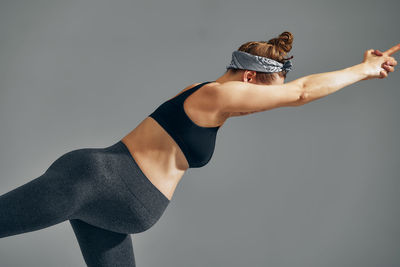 Low section of woman exercising against gray background