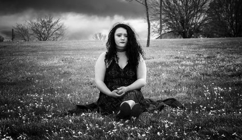 Thoughtful woman looking away while sitting on field