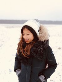 Close-up of young woman standing on beach during winter