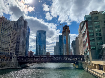 Bridge over river amidst buildings against sky in city