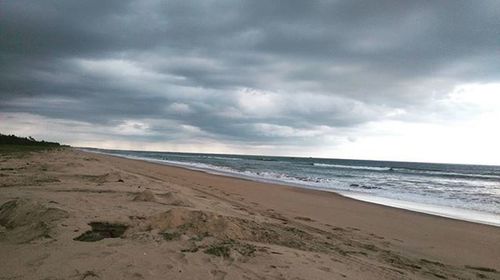 Scenic view of beach against cloudy sky