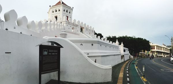 Low angle view of white building by road against sky