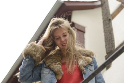 Smiling young woman standing against building