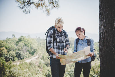 Man and woman reading map at forest