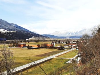 Scenic view of field by houses against sky