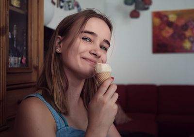 Portrait of smiling girl eating ice cream at home