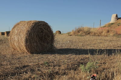 Hay bales on field against clear sky