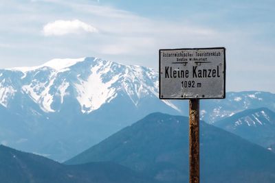 Information sign on snowcapped mountain against sky