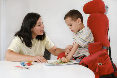 Child with cerebral palsy painting with fingers and hands boy that has health problems developing