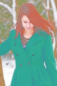 Young woman looking away while standing outdoors