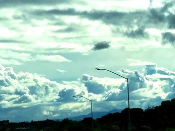 Silhouette of street light against cloudy sky