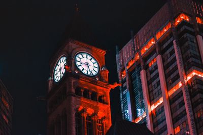 Low angle view of clock tower at night