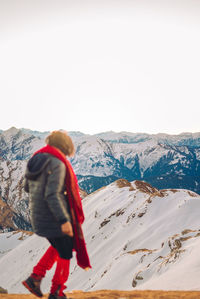 Woman on snowcapped mountain against clear sky