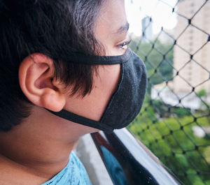 Brazilian boy using mask during the quarantine looking outside.