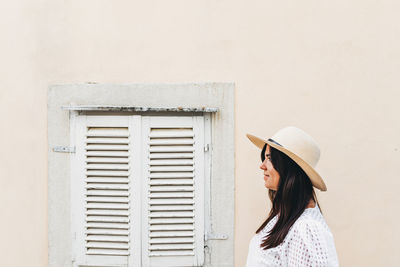 Side view, portrait of a young woman, summer style, hat, pastel, wall, window.