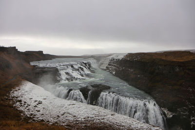 Scenic view during winter of waterfall against clouded sky in iceland