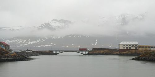 Scenic view of river by buildings against sky during winter