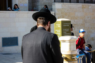 Rear view of people standing against wall