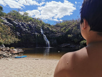 Rear view of shirtless man in water against sky